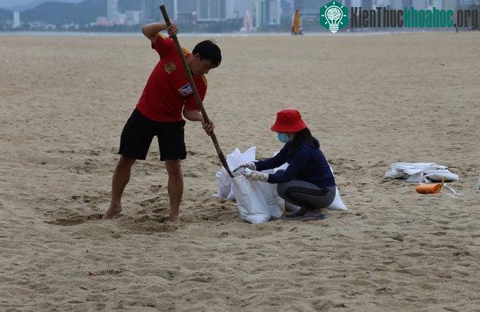 Anh Trí cùng vợ xúc cát bên bờ biển Nha Trang để về dằn mái nhà, ngày 9/11.