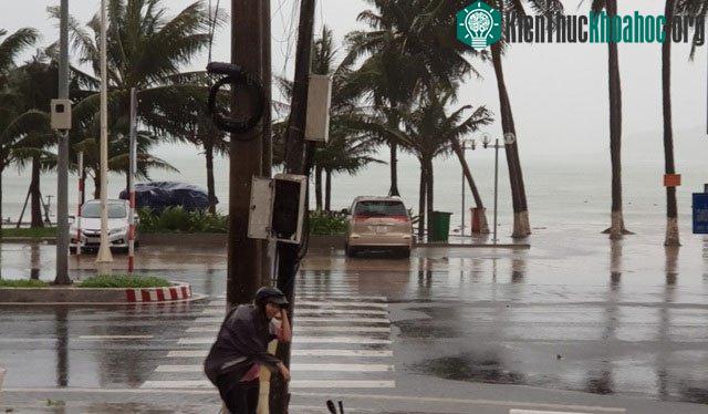 Một người đi đường phải nấp sau cột điện để tránh gió mạnh.