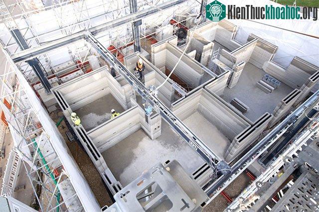 Máy in 3D và thợ xây cùng phối hợp làm việc.