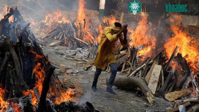 Một người đàn ông chạy giữa hai hàng thi thể đang được hỏa táng.