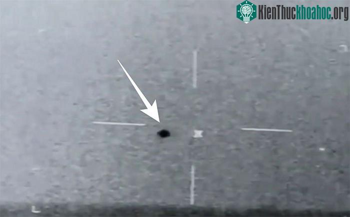 UFO là một đốm gần tròn sẫm màu nằm phía trên đường chân trời.